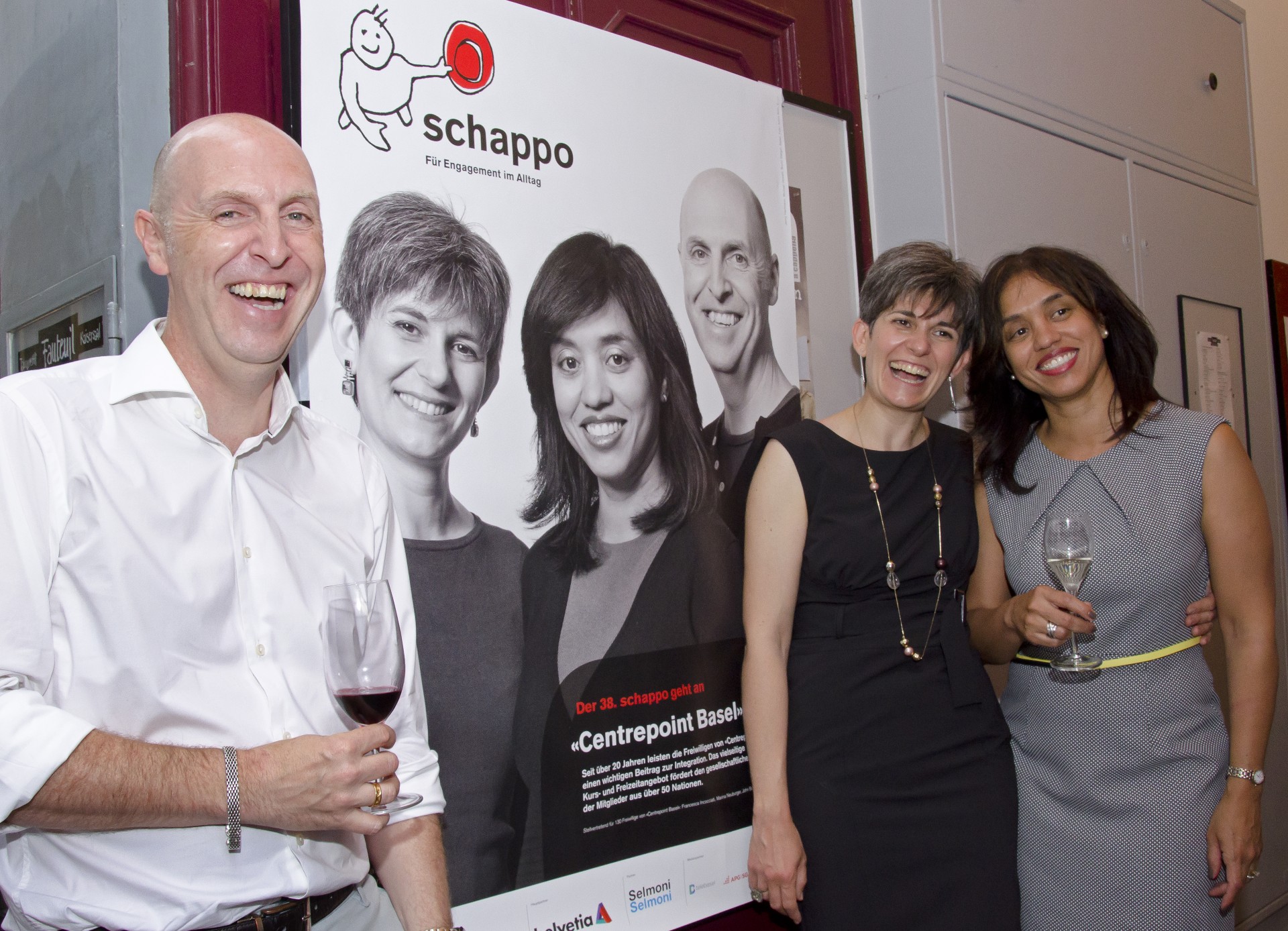 Members of the Centrepoint Board in front of a poster celebrating Centrepoint receiving Basel Stadt's Schappo award in 2017
