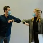 Man and woman touching elbows and wearing facemasks