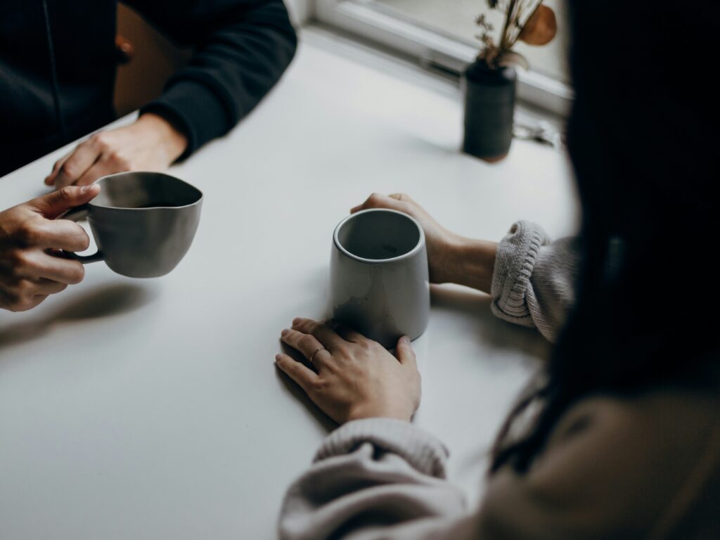 Two people drinking cups of coffee facing each other