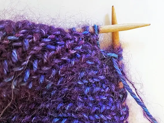 Mauve knitting on a pair of knitting needles