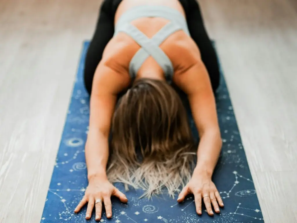 a woman on a yoga mat with her head face down on the mat and her arms stretched forward in a yoga pose